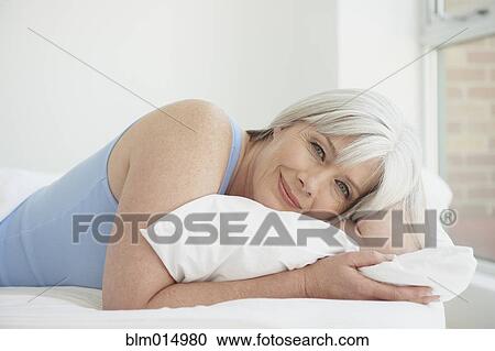 Stock Image - Caucasian woman laying in bed. Fotosearch