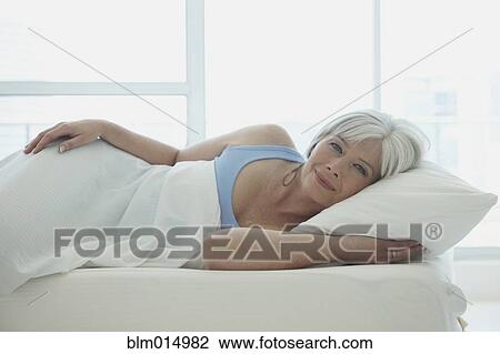 Stock Image - Caucasian woman laying in bed. Fotosearch