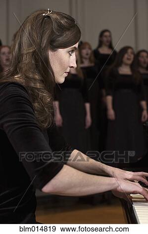 Caucasian woman playing piano for choir View Large Photo Image Stock Photo - Caucasian woman playing piano for choir. Fotosearch