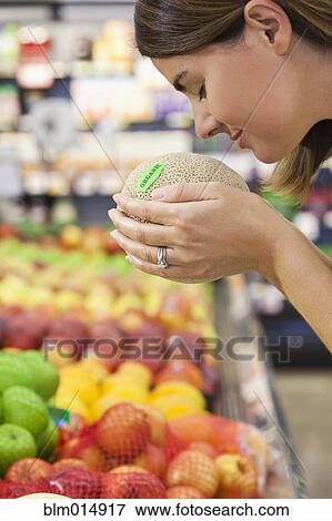 Caucasian woman smelling cantaloupe in grocery store View Large Photo Image Stock Photo - Caucasian woman smelling cantaloupe in grocery store. Fotosearch