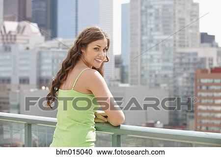 Stock Image - Caucasian woman standing on city balcony. Fotosearch