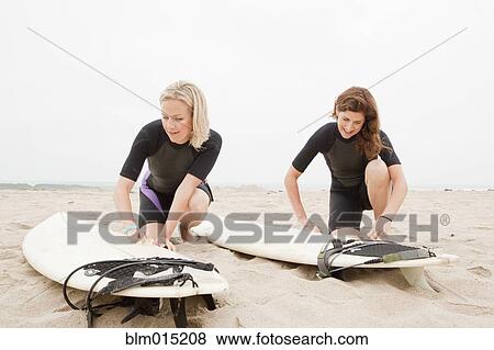 Stock Photo - Caucasian women preparing to go surfing. Fotosearch