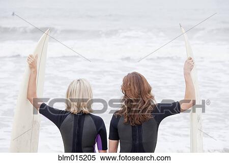 Stock Photography - Caucasian women standing with surfboards. Fotosearch