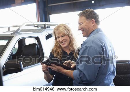 Stock Photograph - Caucasian worker and customer in auto repair shop. Fotosearch