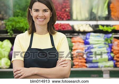 Stock Image - Caucasian worker in produce section of grocery store. Fotosearch