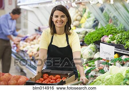 Stock Photograph - Caucasian worker in produce section of grocery store. Fotosearch