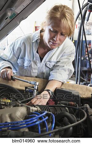 Stock Image - Caucasian worker working on automobile engine. Fotosearch