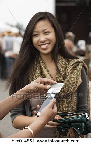 Stock Image - Chinese woman paying with credit card at flea market. Fotosearch