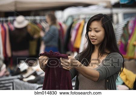Stock Image - Chinese woman shopping at flea market. Fotosearch