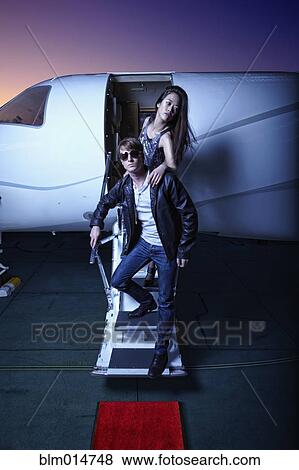 Couple waking down steps of private jet View Large Photo Image Stock Photo - Couple waking down steps of private jet. Fotosearch