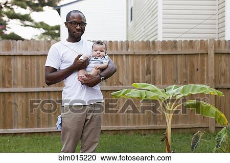 Stock Image - Father holding baby outdoors. Fotosearch