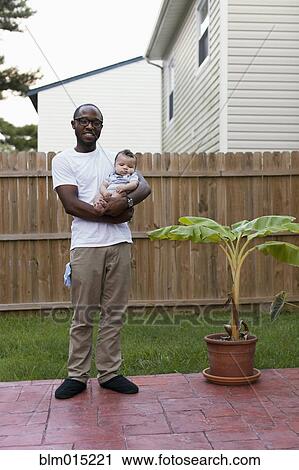 Stock Image - Father holding baby outdoors. Fotosearch