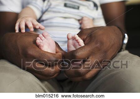 Stock Photograph - Father holding baby's small feet. Fotosearch