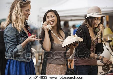 Friends playing with old-fashioned telephones at flea market View Large Photo Image Stock Image - Friends playing with old-fashioned telephones at flea market. Fotosearch