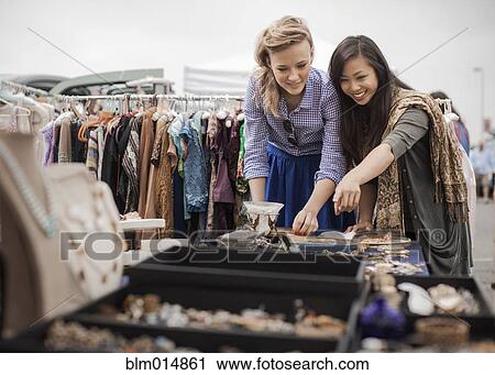 Stock Image - Friends shopping for jewelry in flea market. Fotosearch