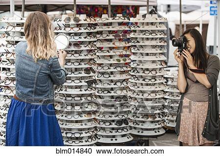 Friends trying on glasses in flea market View Large Photo Image Stock Image - Friends trying on glasses in flea market. Fotosearch