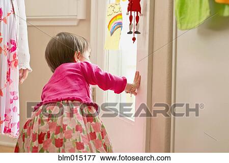 Stock Photo - Hispanic girl looking out door. Fotosearch
