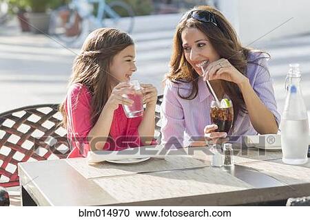 Stock Image - Hispanic mother and daughter eating at cafe. Fotosearch