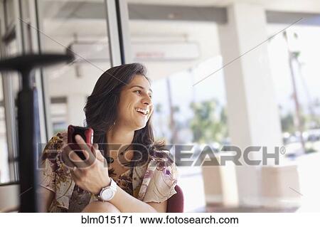 Stock Image - Hispanic woman holding cell phone. Fotosearch