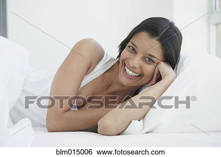 Stock Photograph - Hispanic woman laying in bed. Fotosearch