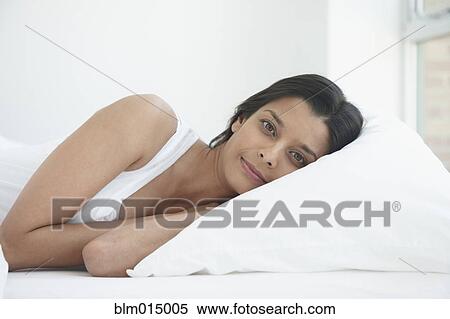 Stock Photography - Hispanic woman laying in bed. Fotosearch