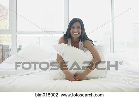 Stock Image - Hispanic woman sitting in bed. Fotosearch