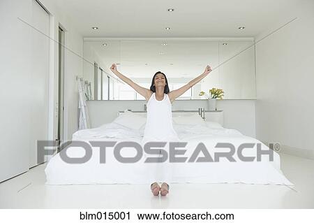 Hispanic woman sitting on bed with arms outstretched View Large Photo Image Stock Image - Hispanic woman sitting on bed with arms outstretched. Fotosearch