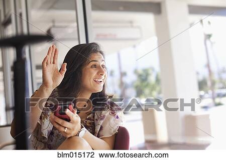 Hispanic woman waving and holding cell phone View Large Photo Image Stock Image - Hispanic woman waving and holding cell phone. Fotosearch