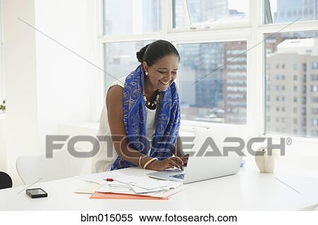 Stock Photography - Indian businesswoman using laptop at desk. Fotosearch