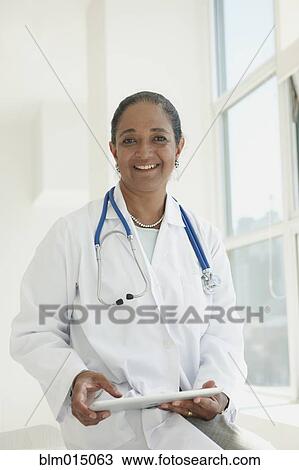 Stock Image - Indian doctor holding digital tablet. Fotosearch