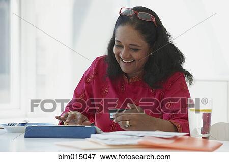 Stock Photo - Indian woman shopping online with credit card. Fotosearch