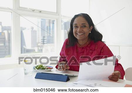 Stock Photograph - Indian woman working and eating lunch. Fotosearch