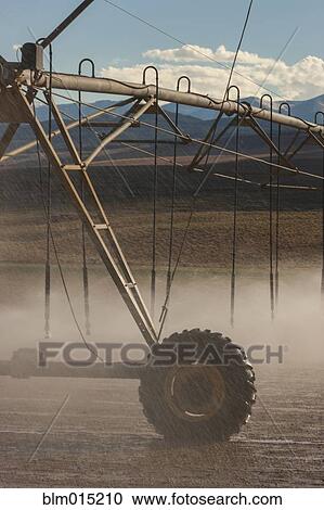 Stock Image - Irrigation sprinklers watering field. Fotosearch