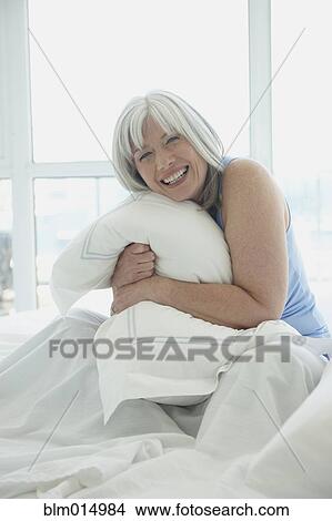 Picture - Laughing Caucasian woman sitting in bed. Fotosearch