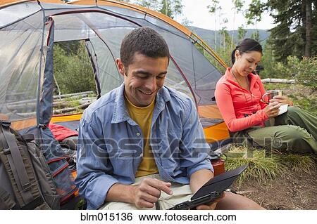 Man using digital tablet while camping View Large Photo Image Stock Photograph - Man using digital tablet while camping. Fotosearch