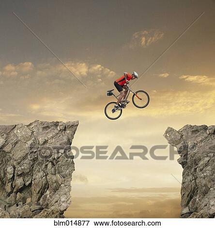 Mixed race bicyclist jumping over canyon View Large Photo Image Stock Photo - Mixed race bicyclist jumping over canyon. Fotosearch
