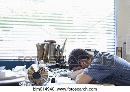 Stock Image - Mixed race man laying on desk. Fotosearch