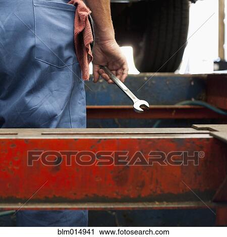 Stock Image - Mixed race worker holding wrench. Fotosearch