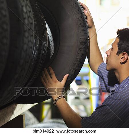 Stock Image - Mixed race worker in tire store. Fotosearch