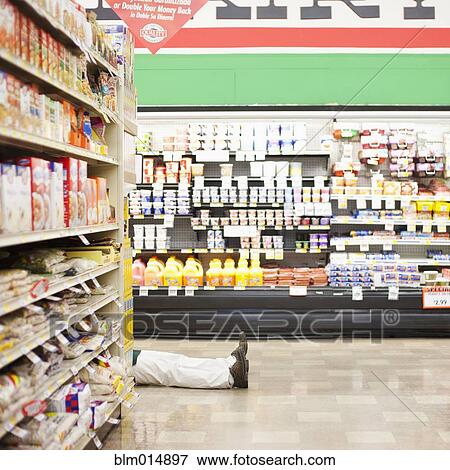 Stock Photo - Mixed race worker laying on floor in grocery store. Fotosearch