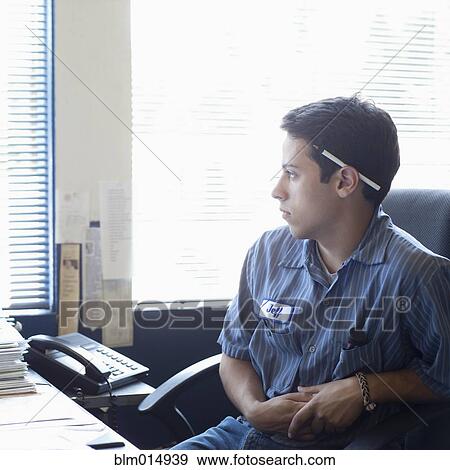 Stock Photo - Mixed race worker sitting at desk. Fotosearch