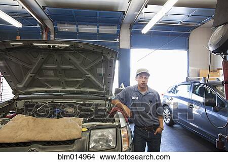 Picture - Mixed race worker standing near automobile engine. Fotosearch