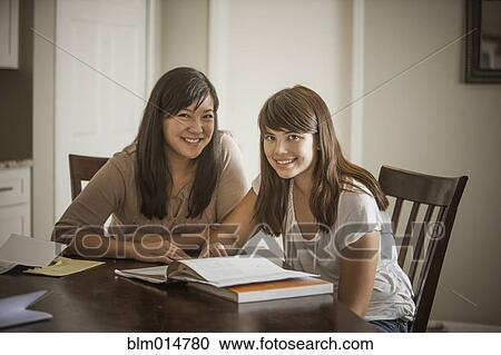 Stock Image - Mother helping daughter with homework. Fotosearch