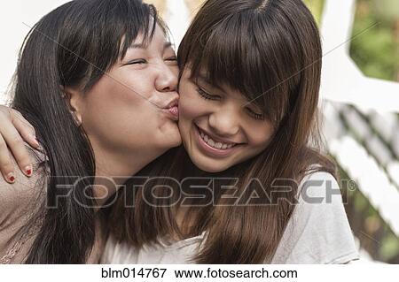 Mother kissing smiling daughter View Large Photo Image Stock Photo - Mother kissing smiling daughter. Fotosearch