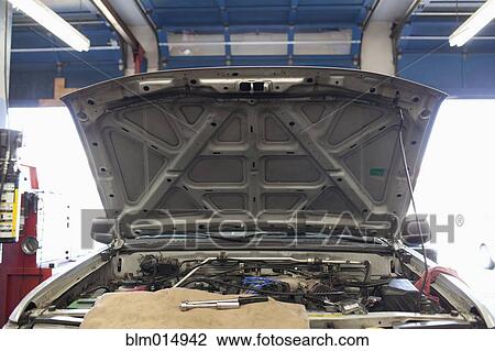 Stock Image - Open automobile hood in repair shop. Fotosearch