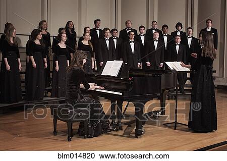 Stock Image - Pianist and choir performing on stage. Fotosearch