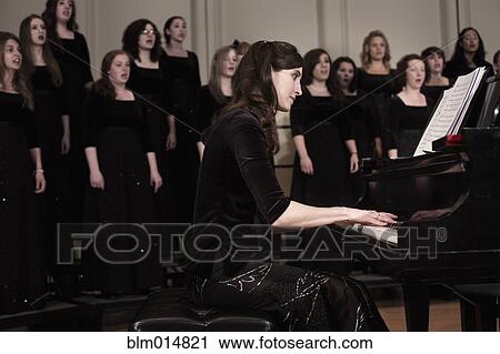 Stock Image - Pianist and choir performing on stage. Fotosearch