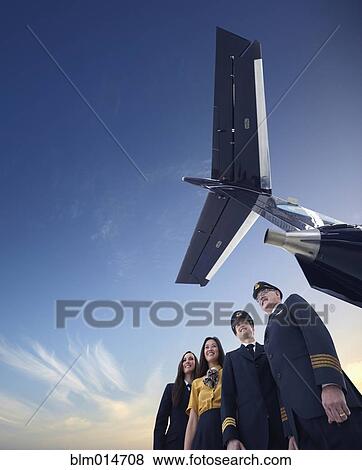 Stock Photo - Pilots and flight staff standing underneath airplane. Fotosearch