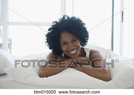 Smiling Black woman laying in bed View Large Photo Image Stock Image - Smiling Black woman laying in bed. Fotosearch
