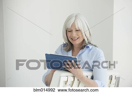 Stock Image - Smiling Caucasian woman using digital tablet. Fotosearch